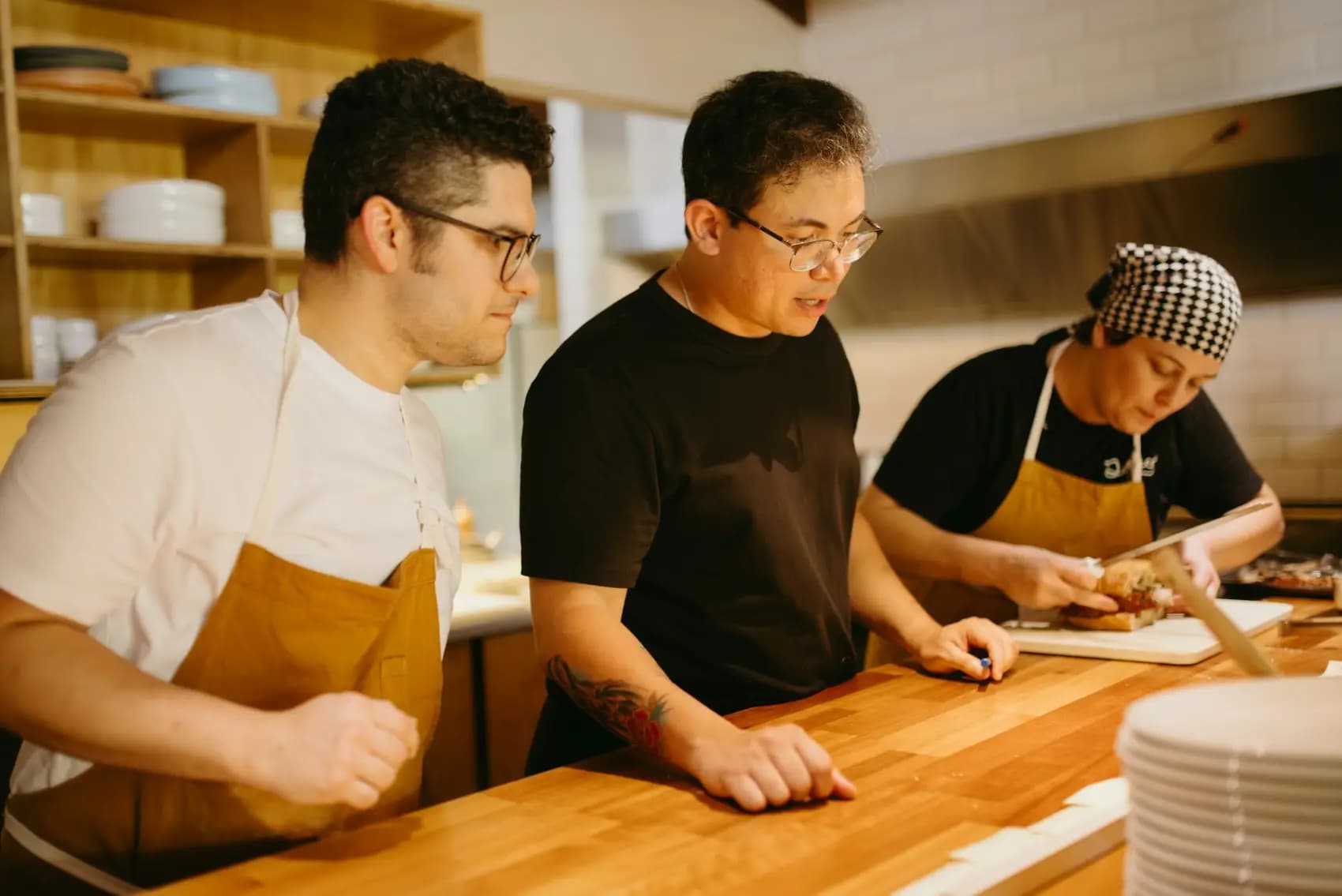 A restaurant team preparing food together at the kitchen counter.